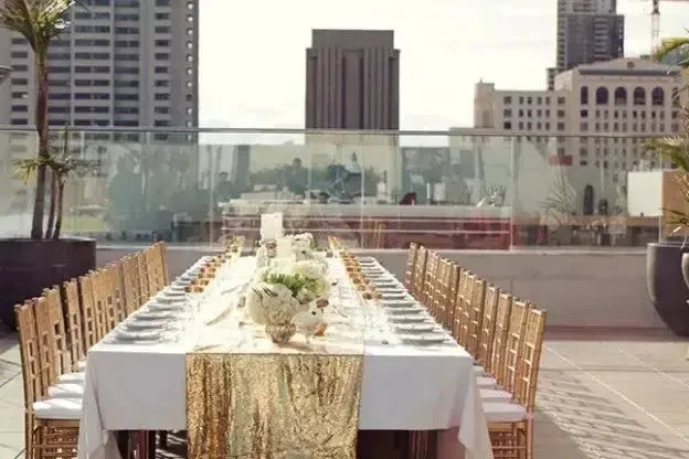 Elegant rooftop wedding rehearsal dinner table with gold decor and city skyline view