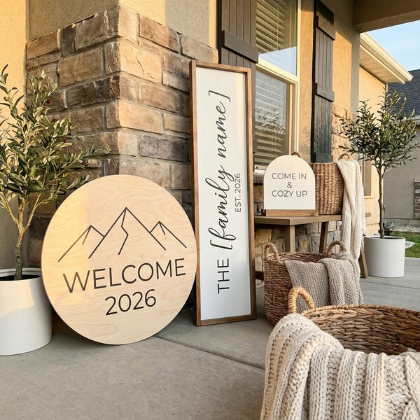 Cozy porch setup with custom wooden welcome sign, family name board, baskets, and knit blankets