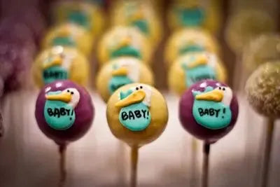 Stork-themed baby shower cake pops with 'baby' text in colorful rows
