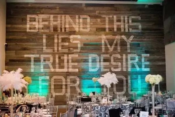 Modern art gallery wedding reception with elegant decor and wooden wall quote art backdrop.