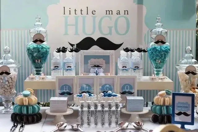 Little man mustache themed dessert table with blue sweets and HUGO sign for birthday party