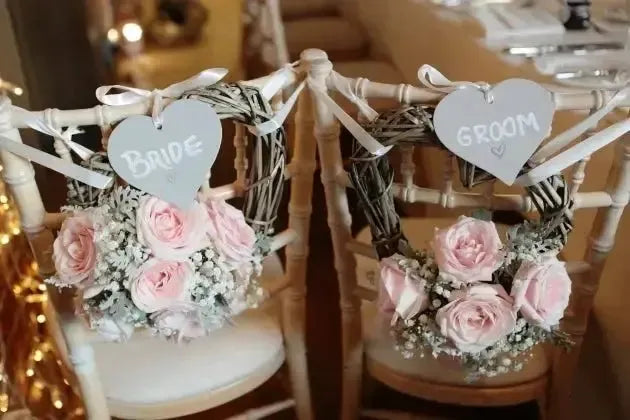 Bride and groom wedding chairs with pink roses, grey heart signs, romantic decor