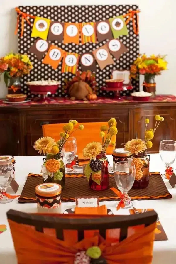 Thanksgiving party table setup with autumn flowers, festive decor, and Give Thanks banner