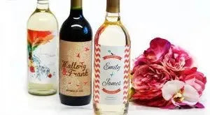 Custom wine bottles with personalized labels beside pink flowers, gift idea