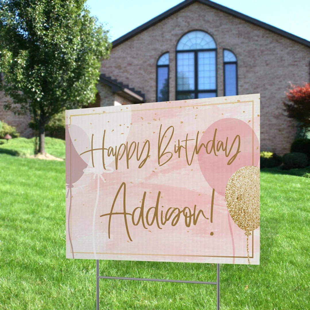 Custom happy birthday yard sign with pink and gold balloons in front of a house