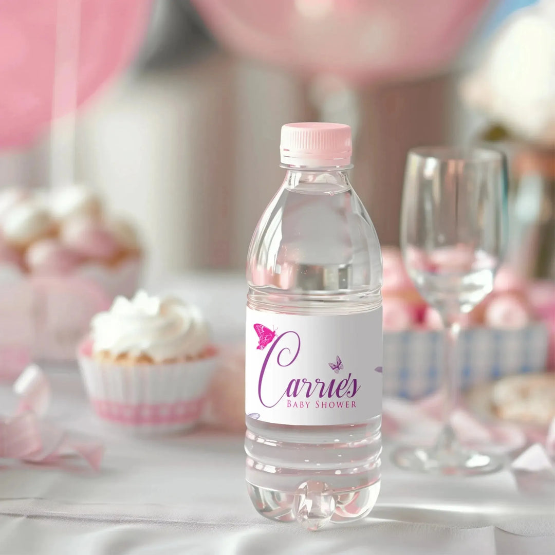 Personalized baby shower water bottle label with pink accents on a bottle, cupcake and glass in background