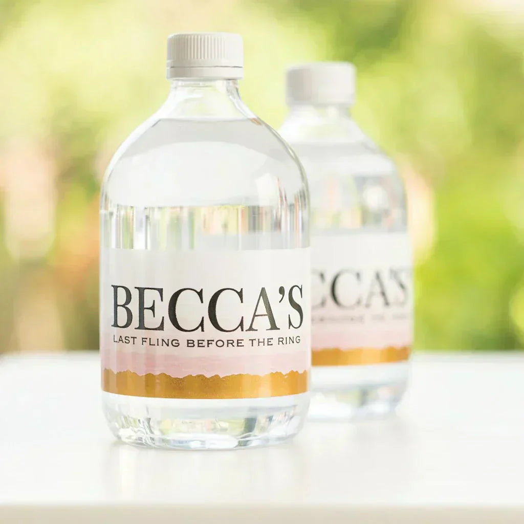 Custom bachelorette water bottle labels with pink and gold design on clear bottles