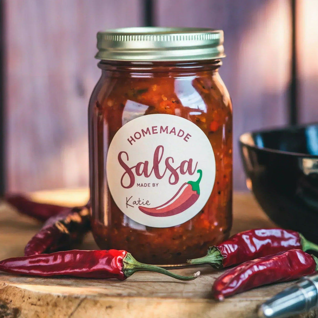 Custom canning label on salsa jar with chili peppers on wooden table
