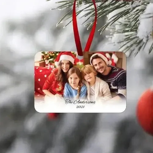 Personalized family Christmas ornament with custom photo and text hanging on a pine tree