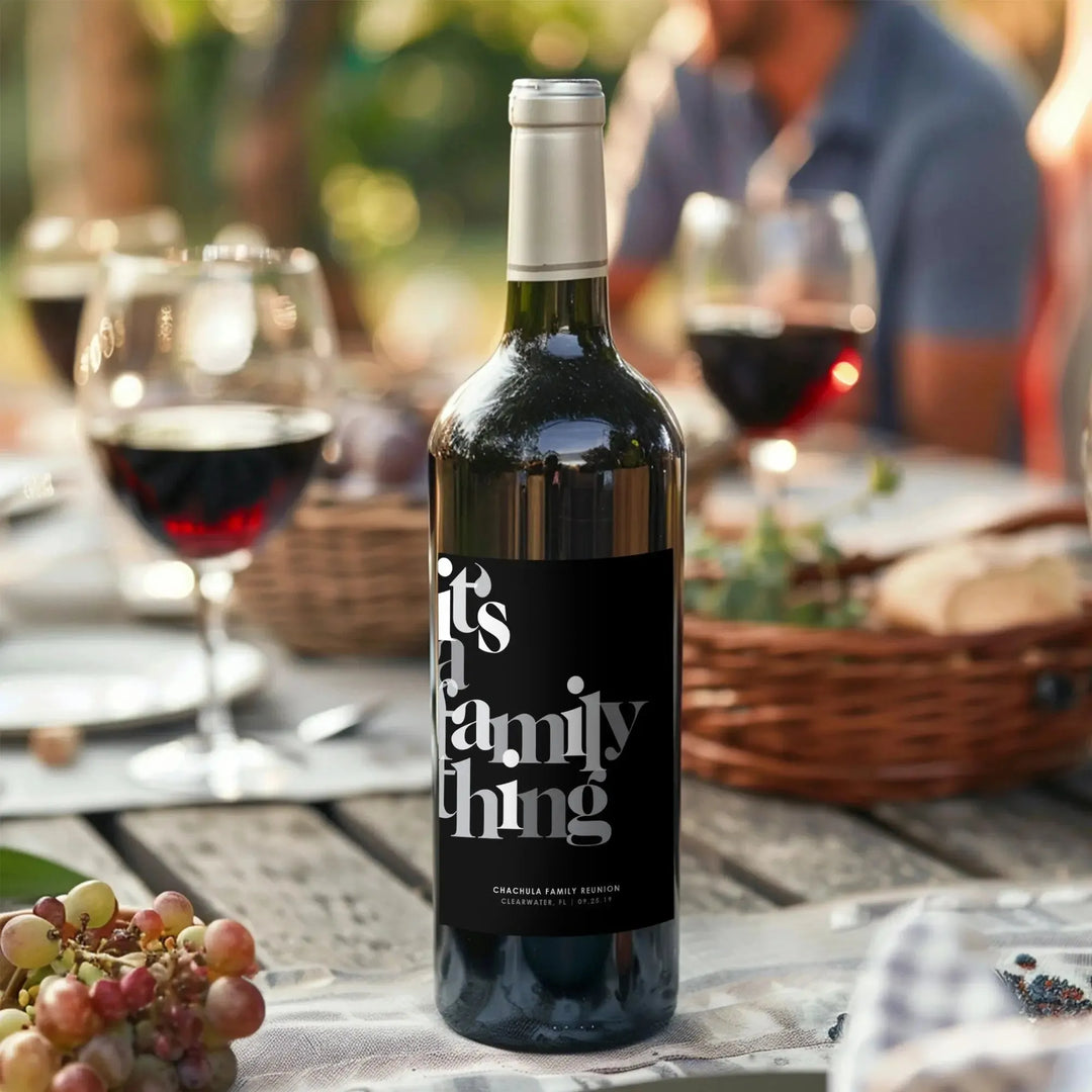 Custom family reunion wine label on bottle at outdoor gathering table with wine glasses