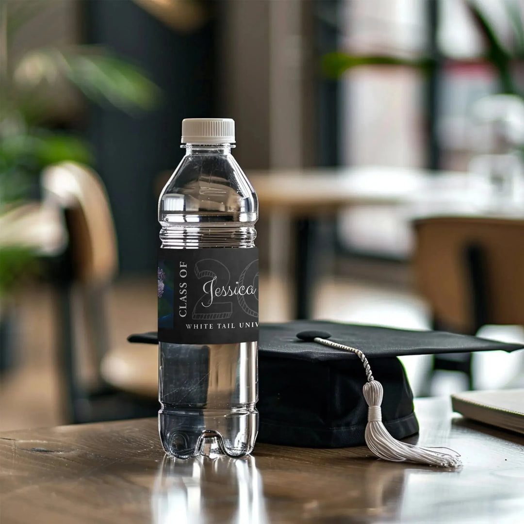Custom graduation water bottle label beside graduation cap on classroom table