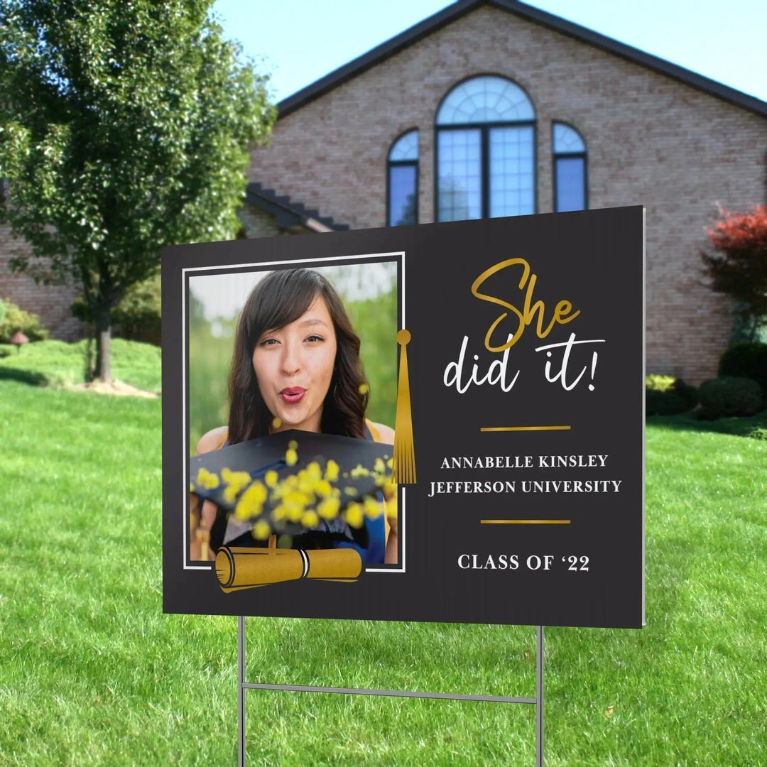 Custom graduation yard sign with photo, diploma, and gold tassel in front of house