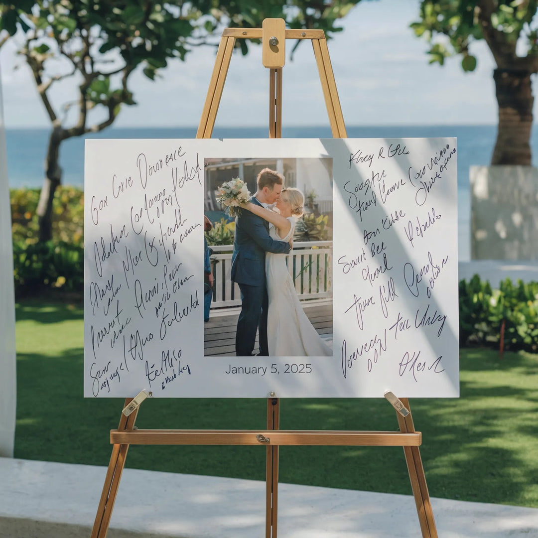 Wedding guest book sign with couple photo and signatures on easel, outdoor beach setting, January 2025