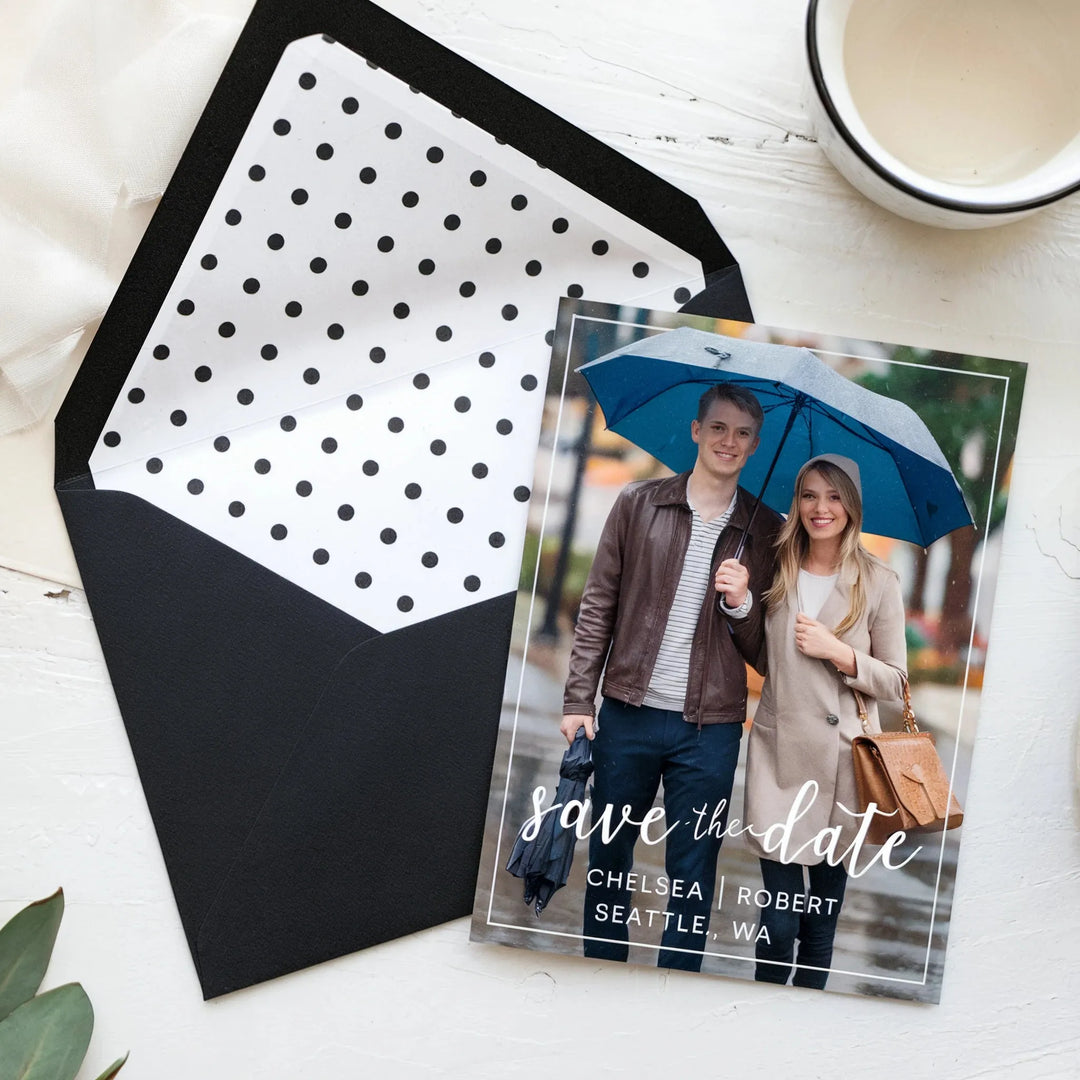 Elegant save the date card with couple under umbrella, black polka dot envelope, wedding stationery
