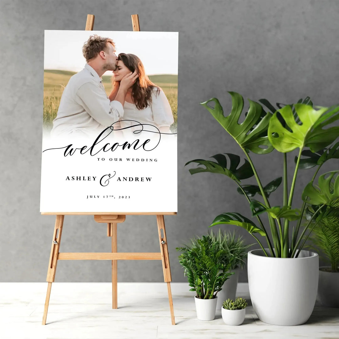 Custom wedding welcome sign on easel with couple photo, modern script, and potted plants