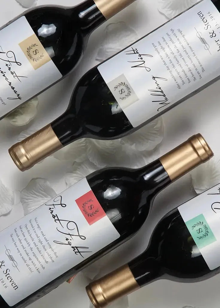 Wedding milestone wine labels on personalized wine bottles with gold caps, flat lay style