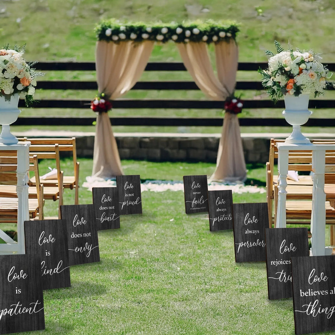 Outdoor wedding aisle decorated with 1 Corinthians 13 wooden signs and floral arrangements