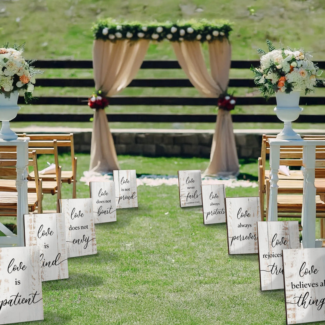 Outdoor wedding aisle decorated with white wooden signs featuring 1 Corinthians 13 love quotes