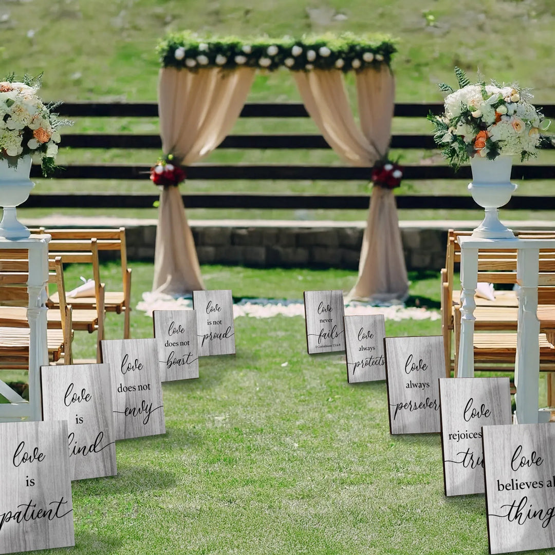 Outdoor wedding aisle decorated with 1 Corinthians 13 love scripture signs and floral arrangements