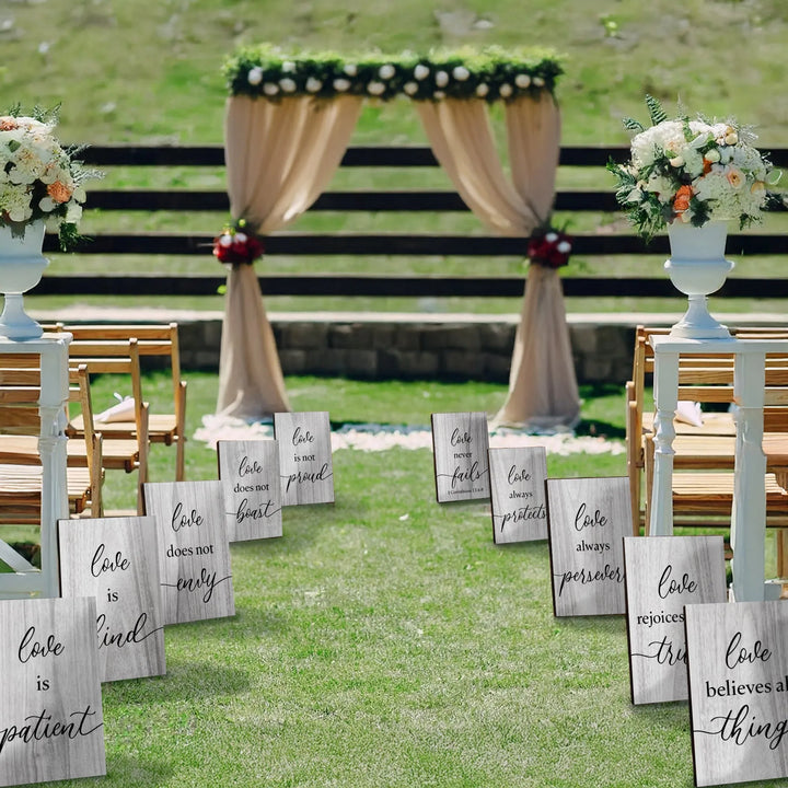 Outdoor wedding aisle decorated with 1 Corinthians 13 love scripture signs and floral arrangements