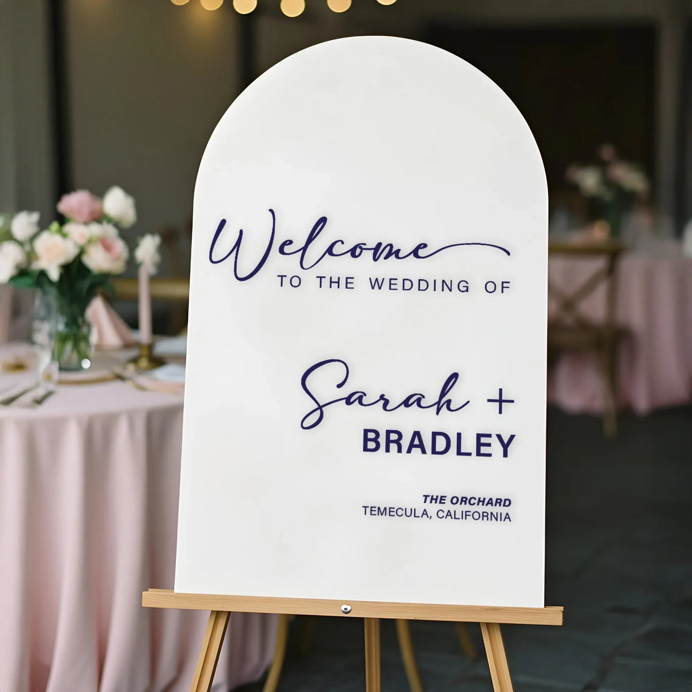 Personalized acrylic wedding welcome sign on an easel at a wedding venue entrance