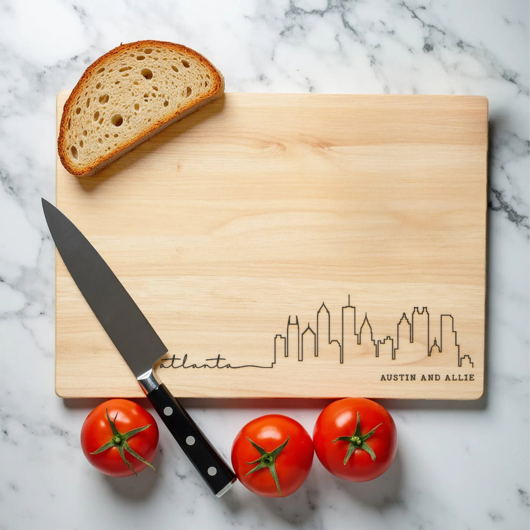 Atlanta skyline engraved wooden cutting board with bread, tomatoes, and knife on marble