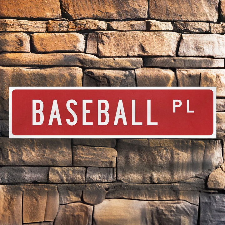 Red metal street sign reading 'BASEBALL PL' mounted on a textured stone wall