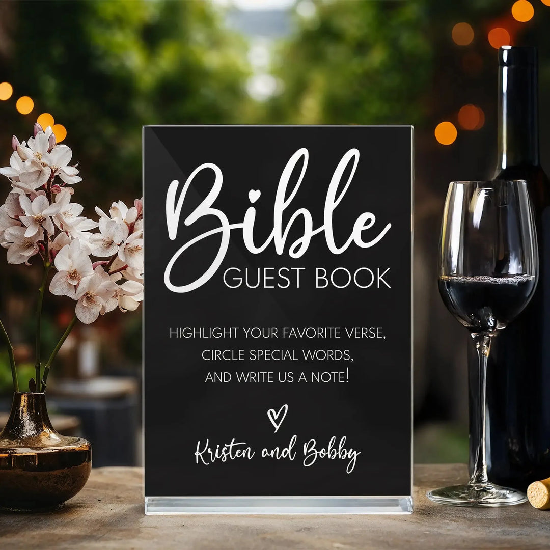 Black Bible guest book wedding sign on table with wine glass and flowers