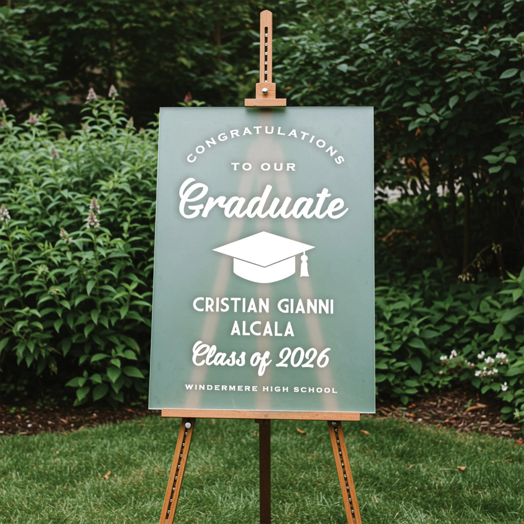 Graduation sign on an easel with a green background and white text, set against a natural outdoor background.