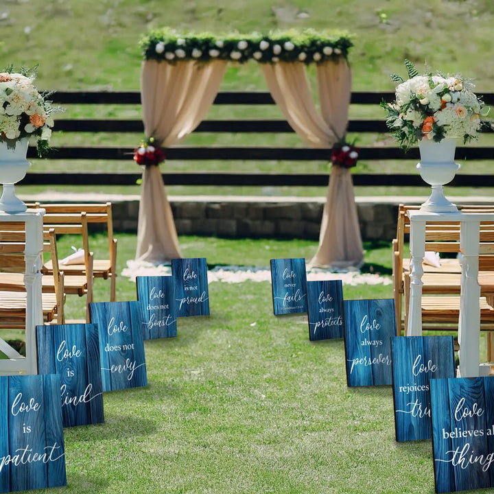 Outdoor wedding aisle with blue wood Corinthians love signs and floral arch backdrop