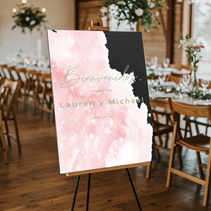 Blush pink and black acrylic Spanish wedding welcome sign for Lauren y Michael on easel in rustic reception venue