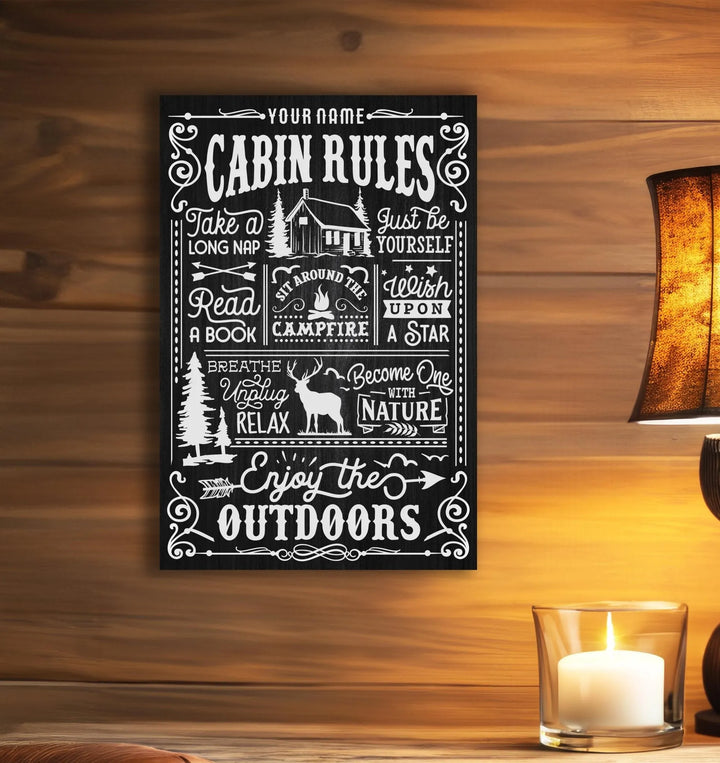 Black metal cabin rules sign with white text and nature illustrations on wooden wall with lamp and candle