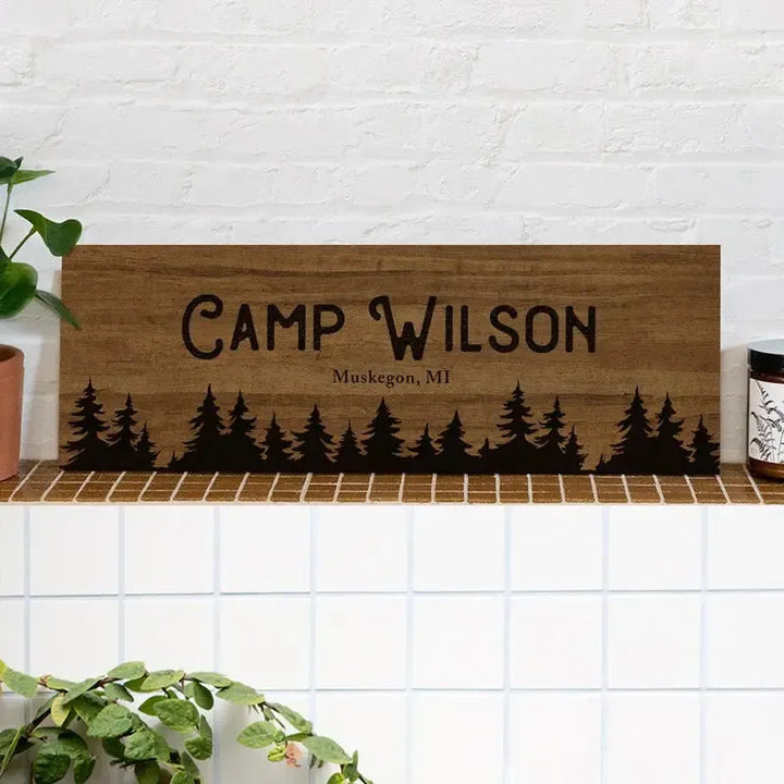 Custom wood camp sign reading Camp Wilson Muskegon MI with tree silhouettes, rustic decor.
