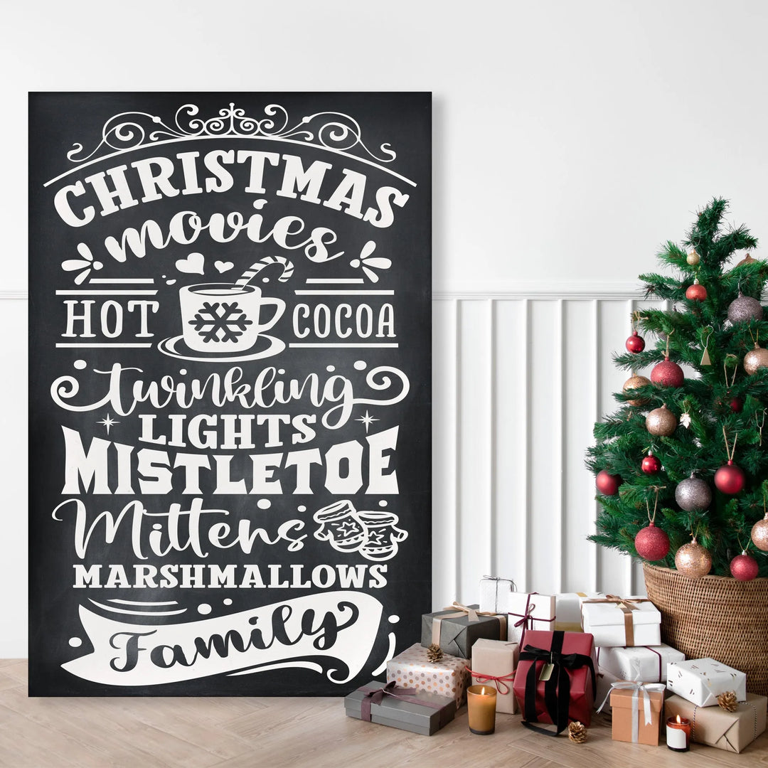 Black Christmas sign with white festive words near decorated Christmas tree and wrapped gifts