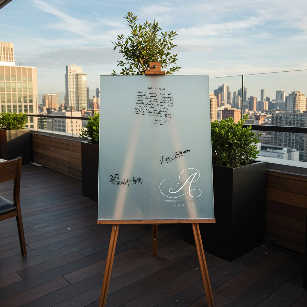 Modern rooftop with glass guest book sign on wooden easel featuring monogram A and date 11.05.25