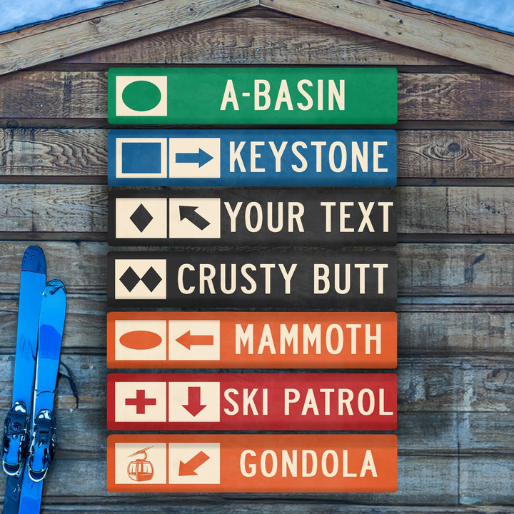 Custom metal ski trail signs with directions for A-Basin, Keystone, Crusty Butt, Mammoth, Ski Patrol, Gondola on wooden wall