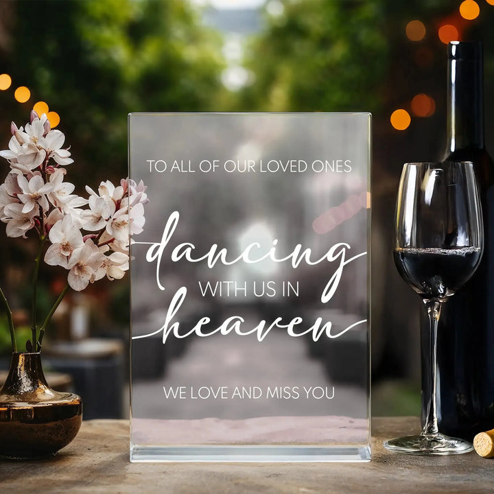Memorial wedding table sign with 'dancing with us in heaven' message, next to flowers and wine glass