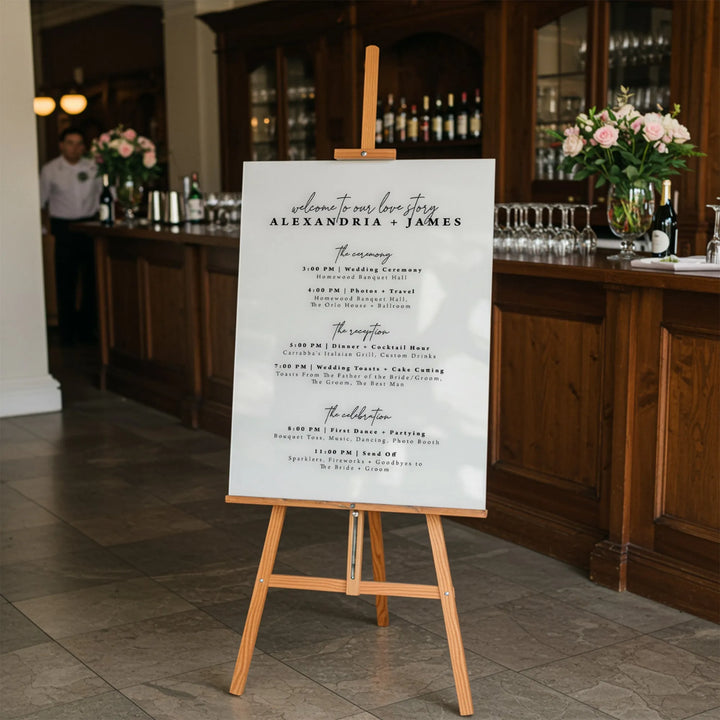 Wedding day timeline sign for Alexandria and James on wooden easel in elegant bar setting
