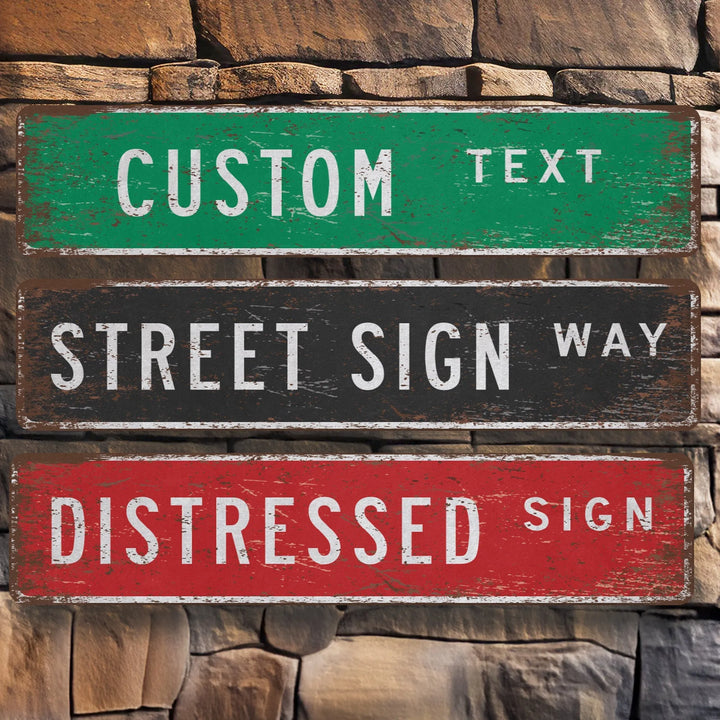 Distressed metal street signs with custom text in green, black, and red on a stone wall background