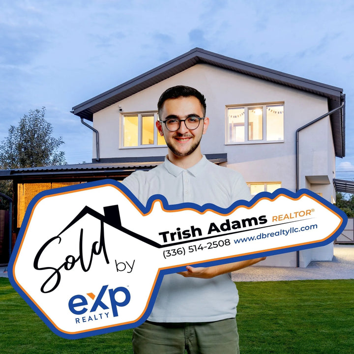 Man holding large Sold by Trish Adams eXp Realty key sign outside modern house at dusk