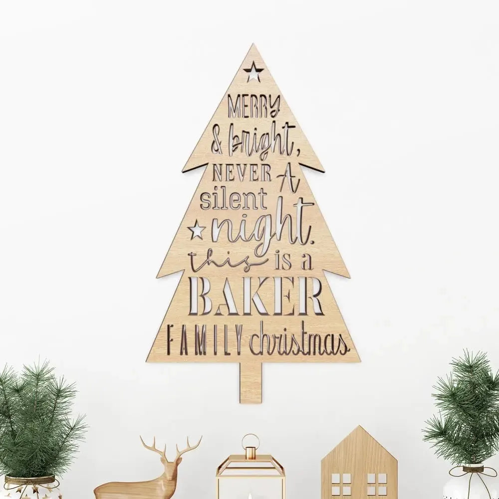 Wood Christmas tree sign with cutout family message, surrounded by mini trees and decor.