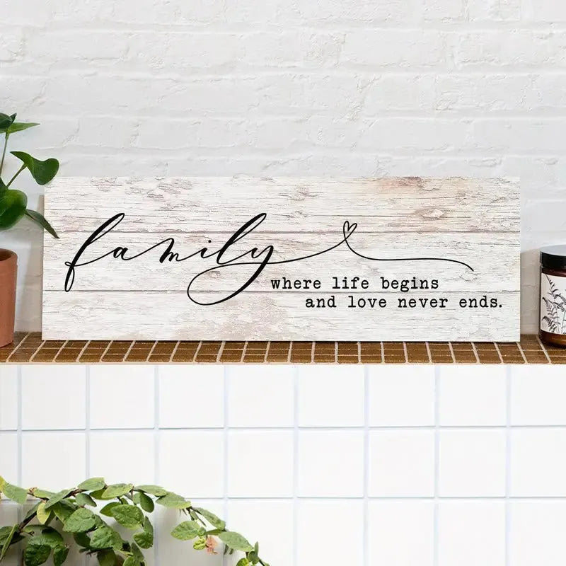 Rustic wood sign with 'family where life begins and love never ends' on a tiled shelf.