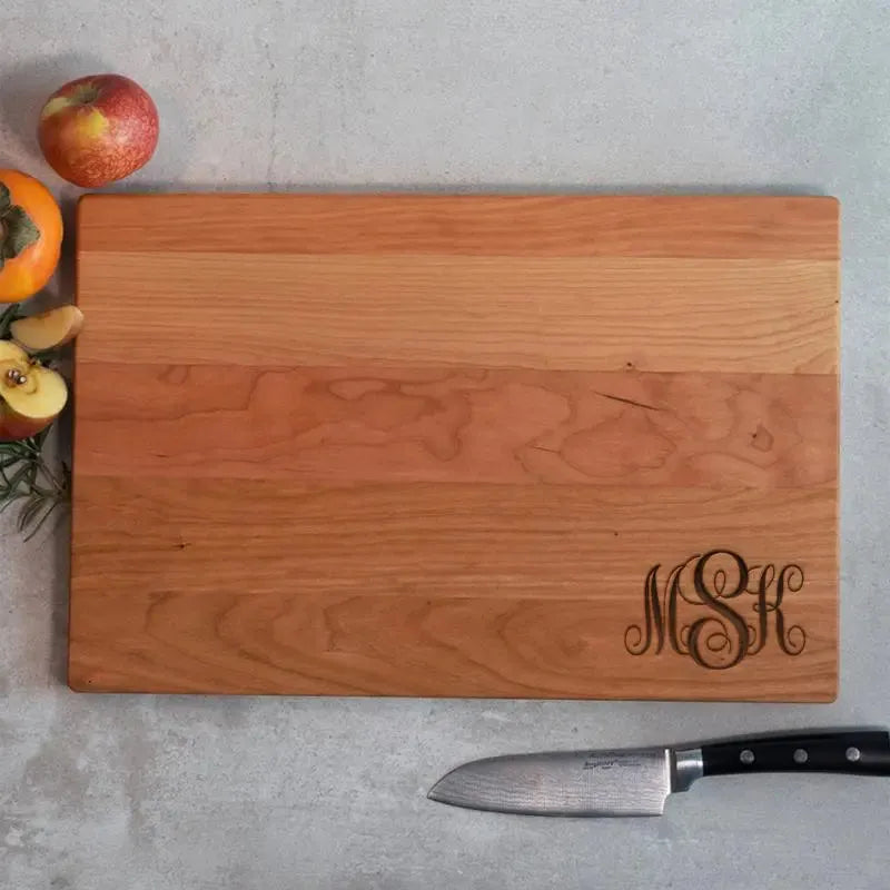 Personalized wooden cutting board with fancy monogram, fruit, and knife on countertop