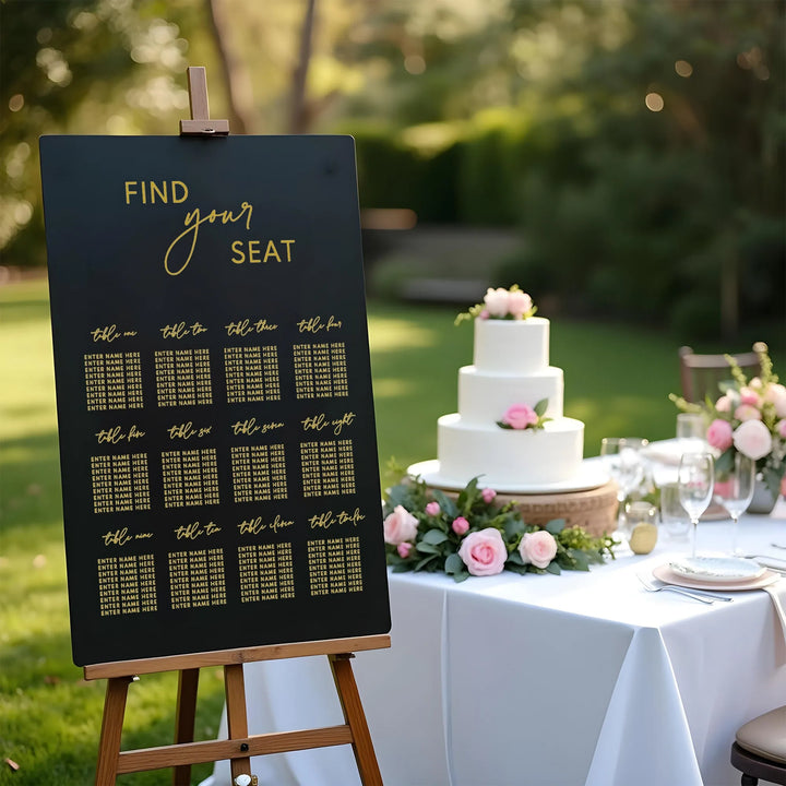 Elegant wedding seating chart on easel with gold lettering beside white tiered cake and floral table decor outdoors