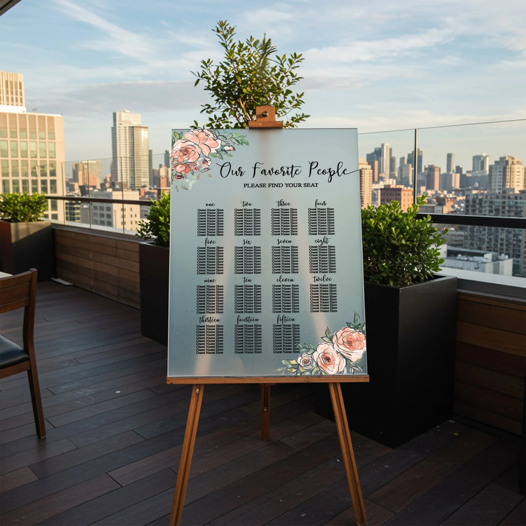 Floral wedding seating chart on wooden easel with city skyline backdrop on rooftop