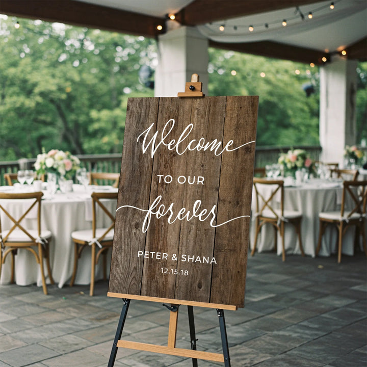 Rustic wooden wedding welcome sign with floral tables and string lights in outdoor reception