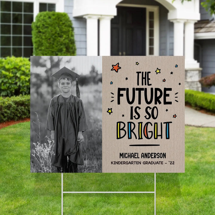 Graduation yard sign with black and white photo of a boy in cap and gown and text The Future Is So Bright