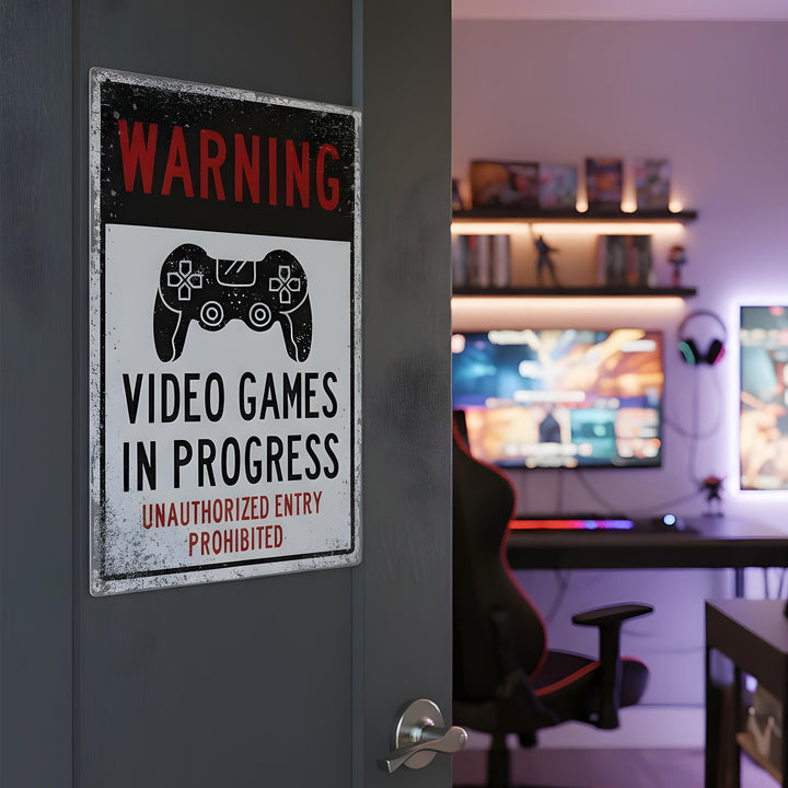 Metal sign on a gray door says 'Warning video games in progress' with a gaming controller icon, gaming room inside