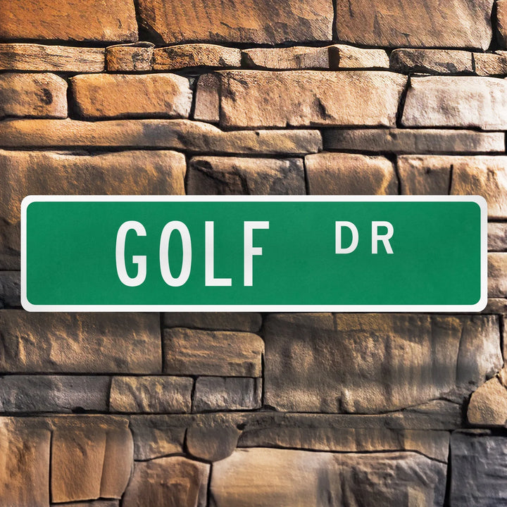 Green metal street sign reading Golf Dr mounted on textured stone wall