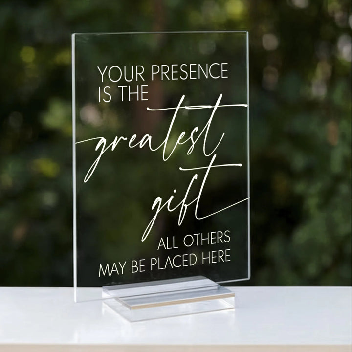 clear acrylic wedding gift sign with white text saying Your presence is the greatest gift